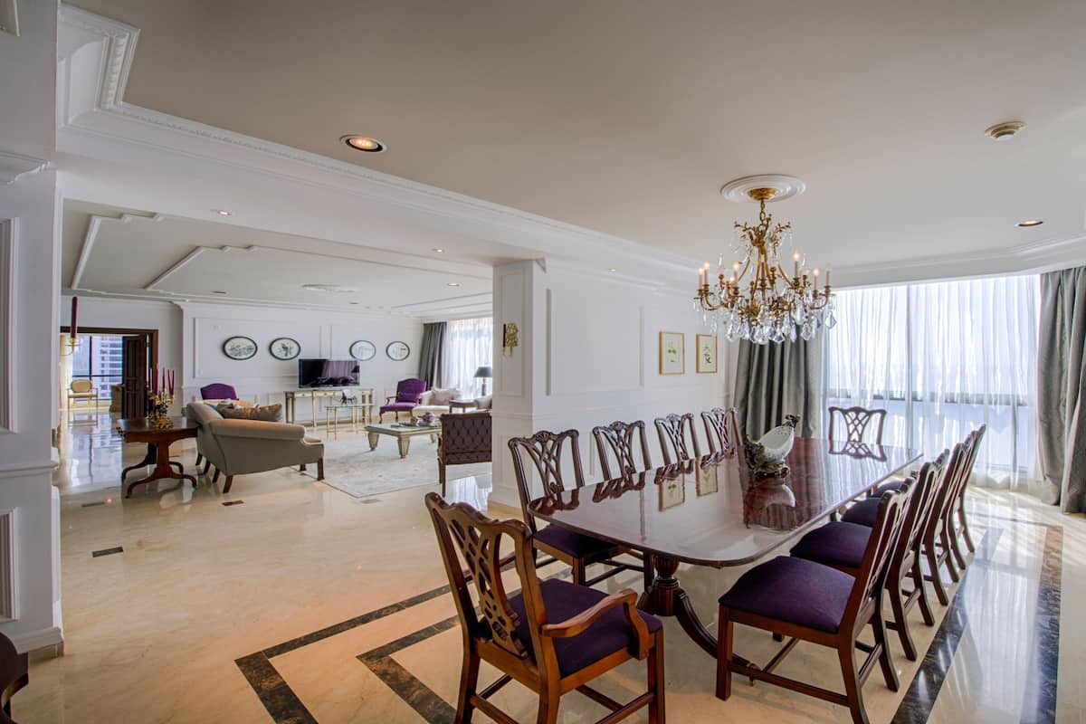 A spacious dining area with a large oval table, multiple chairs, and a chandelier.