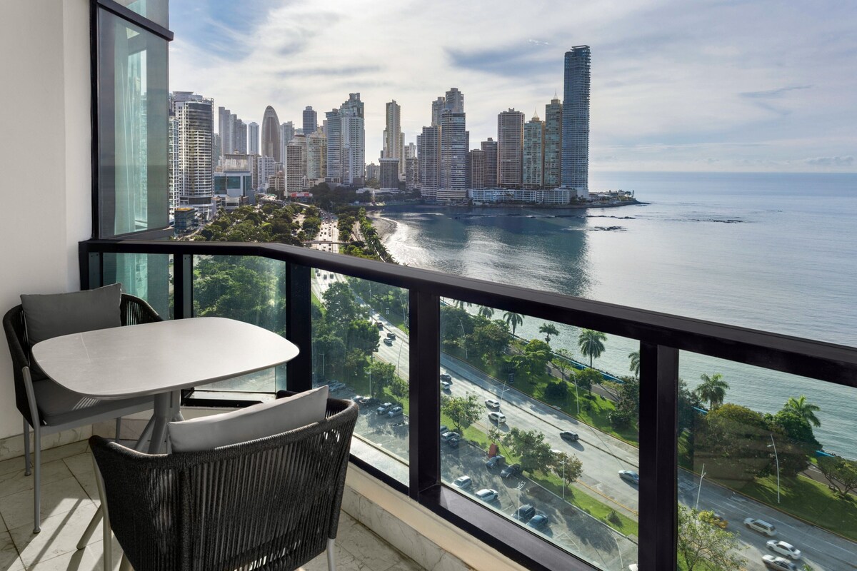 A balcony with a view of a city skyline and a body of water.