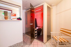 A modern bathroom with a glass partition, a bench, and a red light. - Hotel Alpenrose Kufstein (Kufstein)