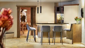 A modern kitchen with a bar area, wooden cabinets, and a dining area with bar stools. - Hotel Alpenrose Kufstein (Kufstein)