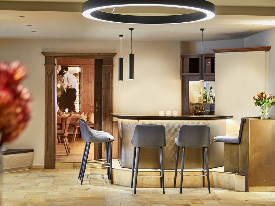 A modern kitchen with a bar area, wooden cabinets, and a dining area with bar stools.