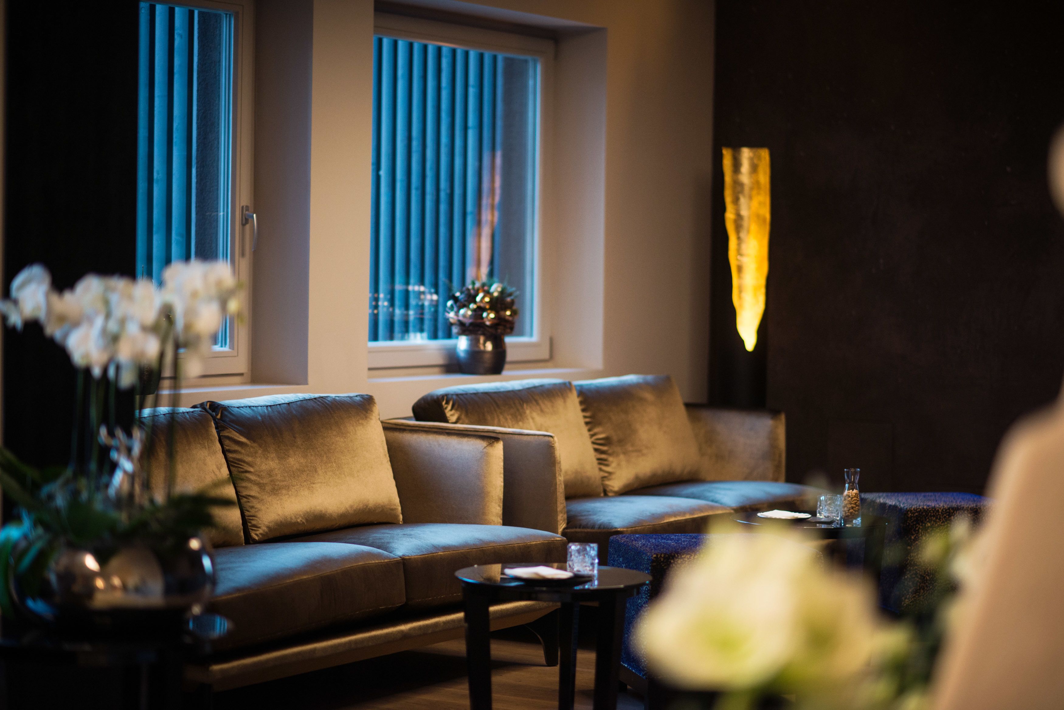 A modern living room with a sofa, a coffee table, and a vase of flowers.