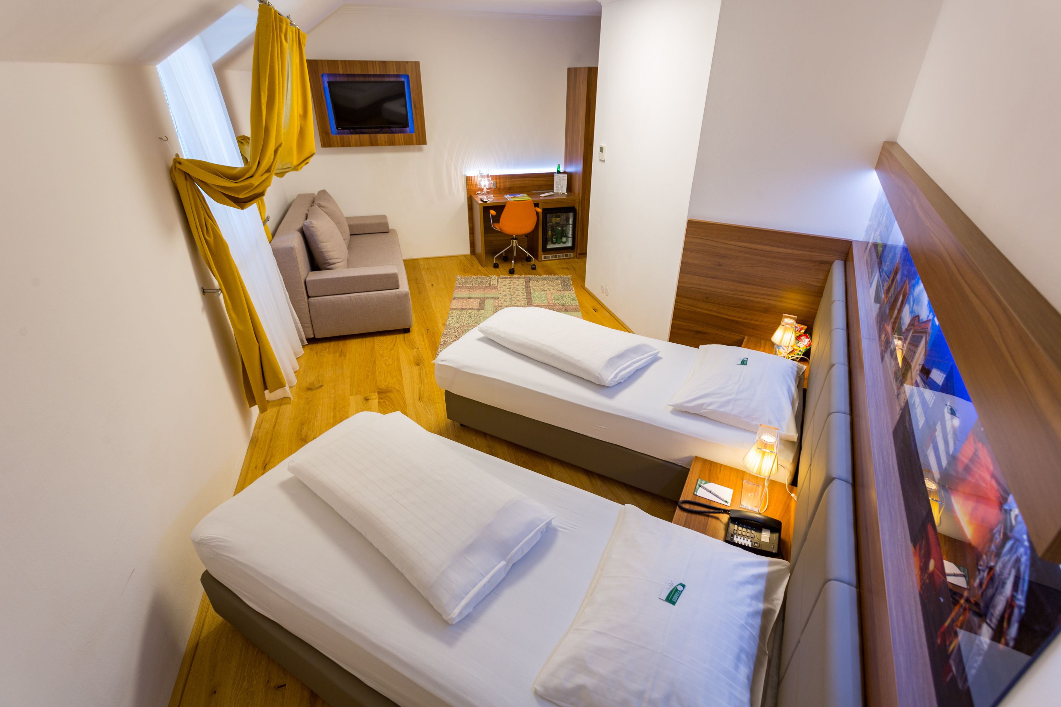 A hotel room with two beds, a desk, a chair, and a TV.