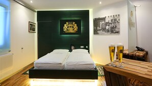 A modern hotel room with a bed, a wooden side table with two glasses of beer, and a framed picture on the wall. - Kongress Hotel (Leoben)