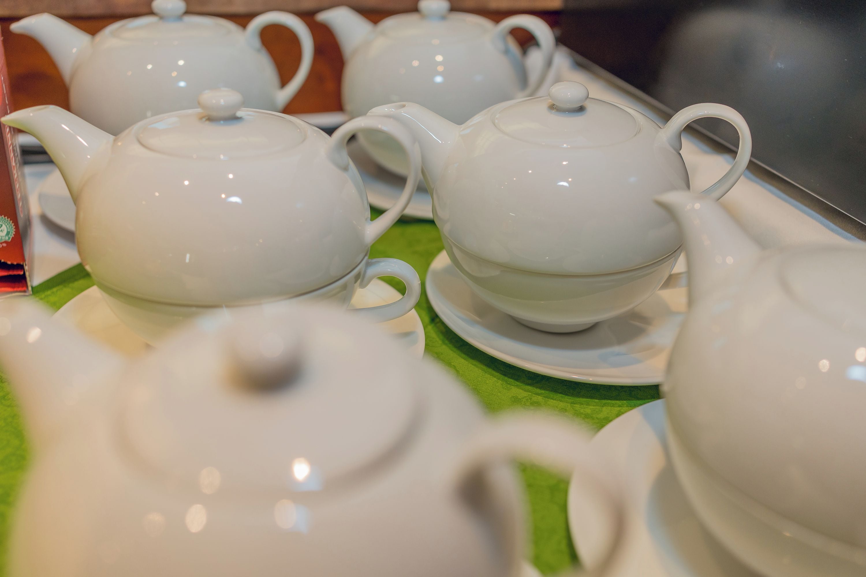 A collection of white teapots and cups arranged on a green surface.