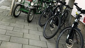Una estación de alquiler de bicicletas con un carrito verde y varias bicicletas estacionadas cerca.