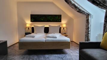 Un dormitorio moderno con una cama grande, dos lámparas de noche, un cuadro sobre la cama y vistas al exterior a través de una ventana con cortinas.