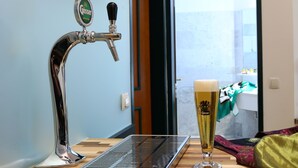 A tap with a beer glass on a wooden table, a keyboard, and a view through a door. - Kongress Hotel (Leoben)