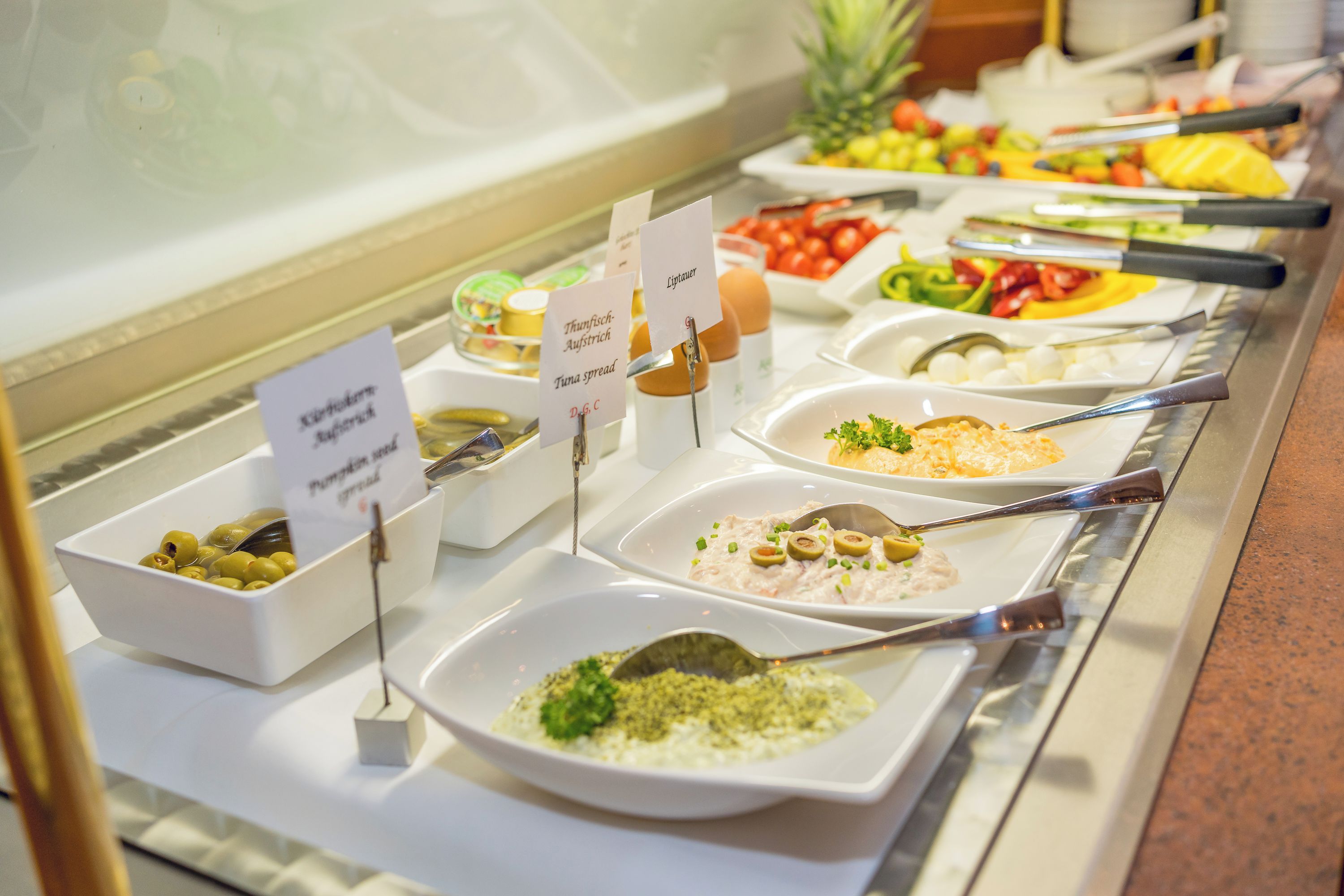 Een buffet met diverse gerechten en labels die het soort eten aangeven.