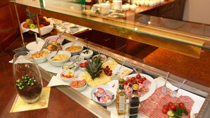 A buffet with various food items and utensils. - Kongress Hotel (Leoben)