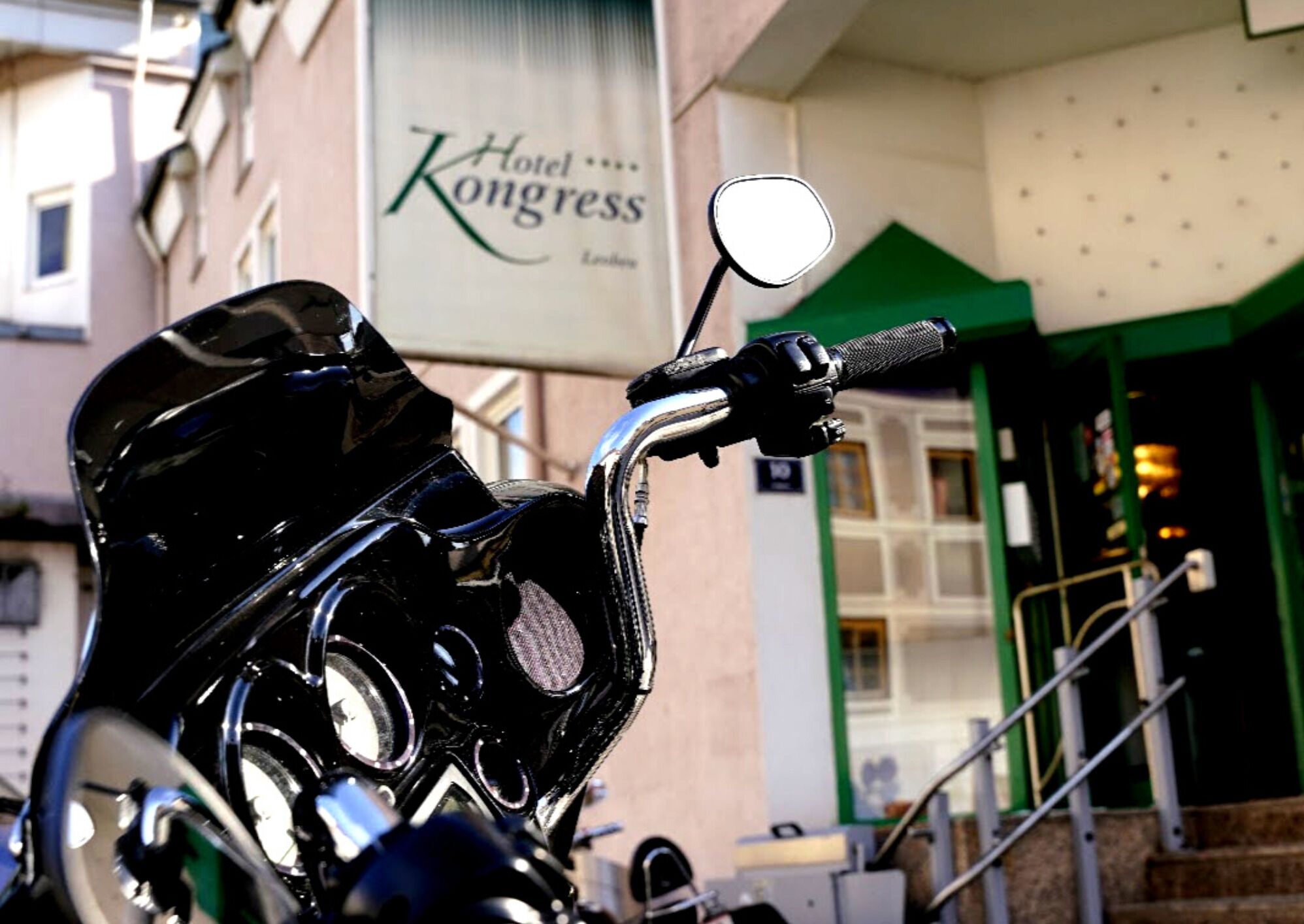 Una motocicleta estacionada frente a un edificio con un letrero que dice "Hotel Kongress".