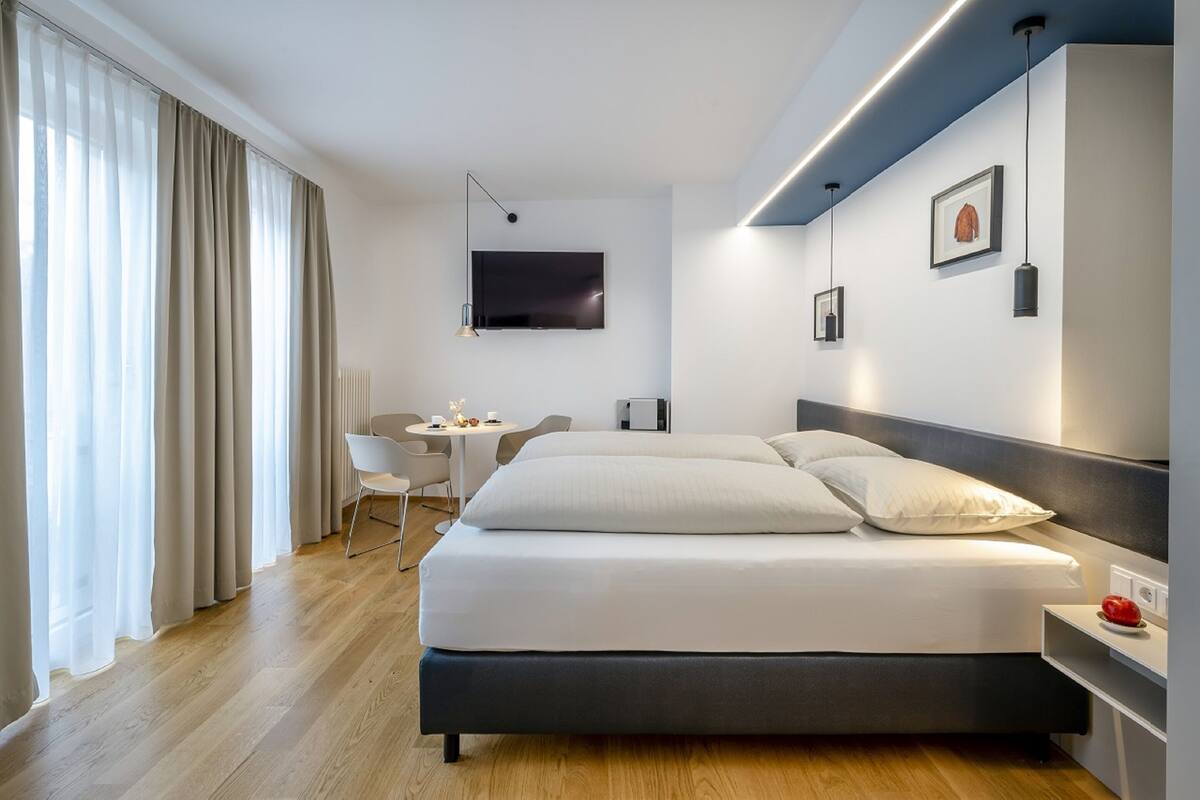 A modern hotel room with a large bed, a desk, and a TV.