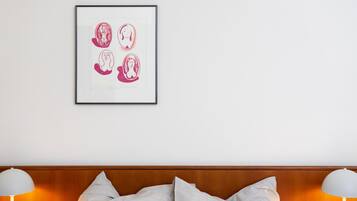 Een hotelkamer met een kunstwerk boven het bed, een houten hoofdeinde en twee bedlampen.