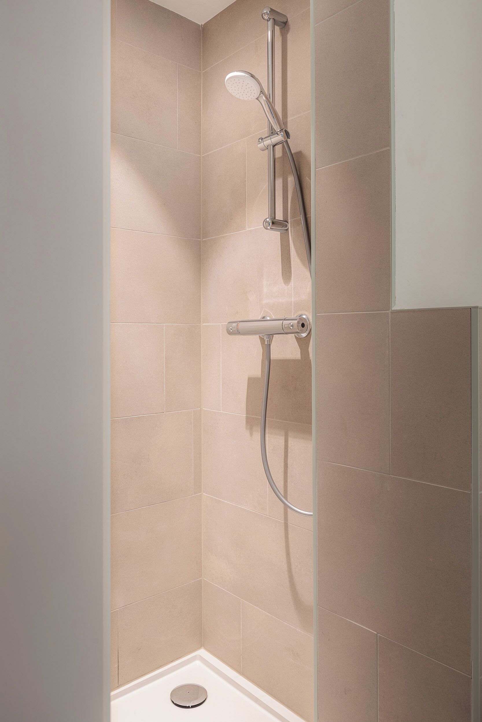 Een douche met een handdouche, een wandmengkraan en een doucheslang.