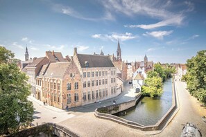 Ein historisches Gebäude mit markantem Eckhaus, einem Kanal und einer Brücke.