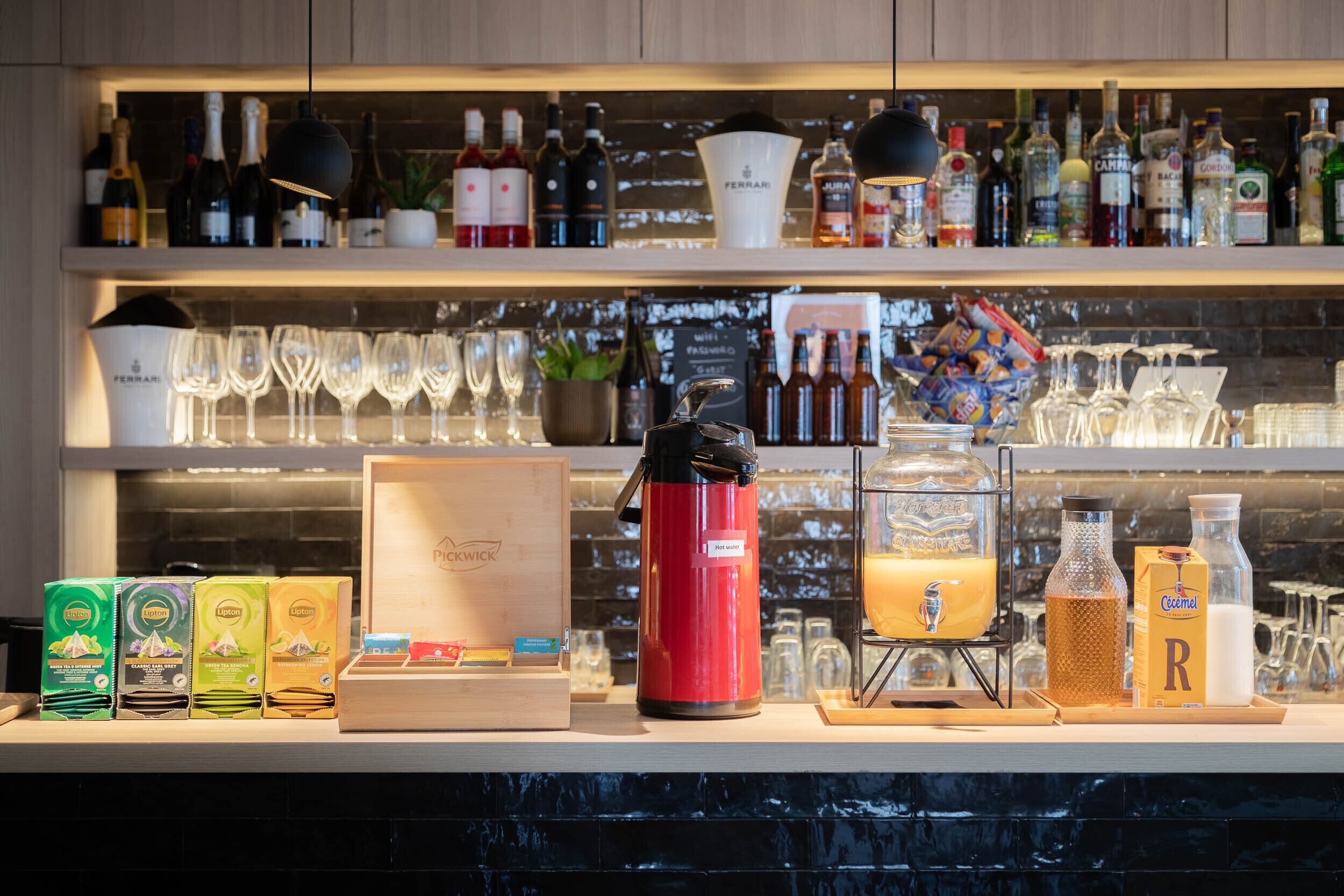 Uma área de bar com prateleiras cheias de garrafas, copos e uma máquina de café.