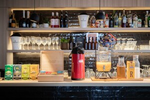 A bar area with shelves of various bottles, glasses, and a coffee machine.