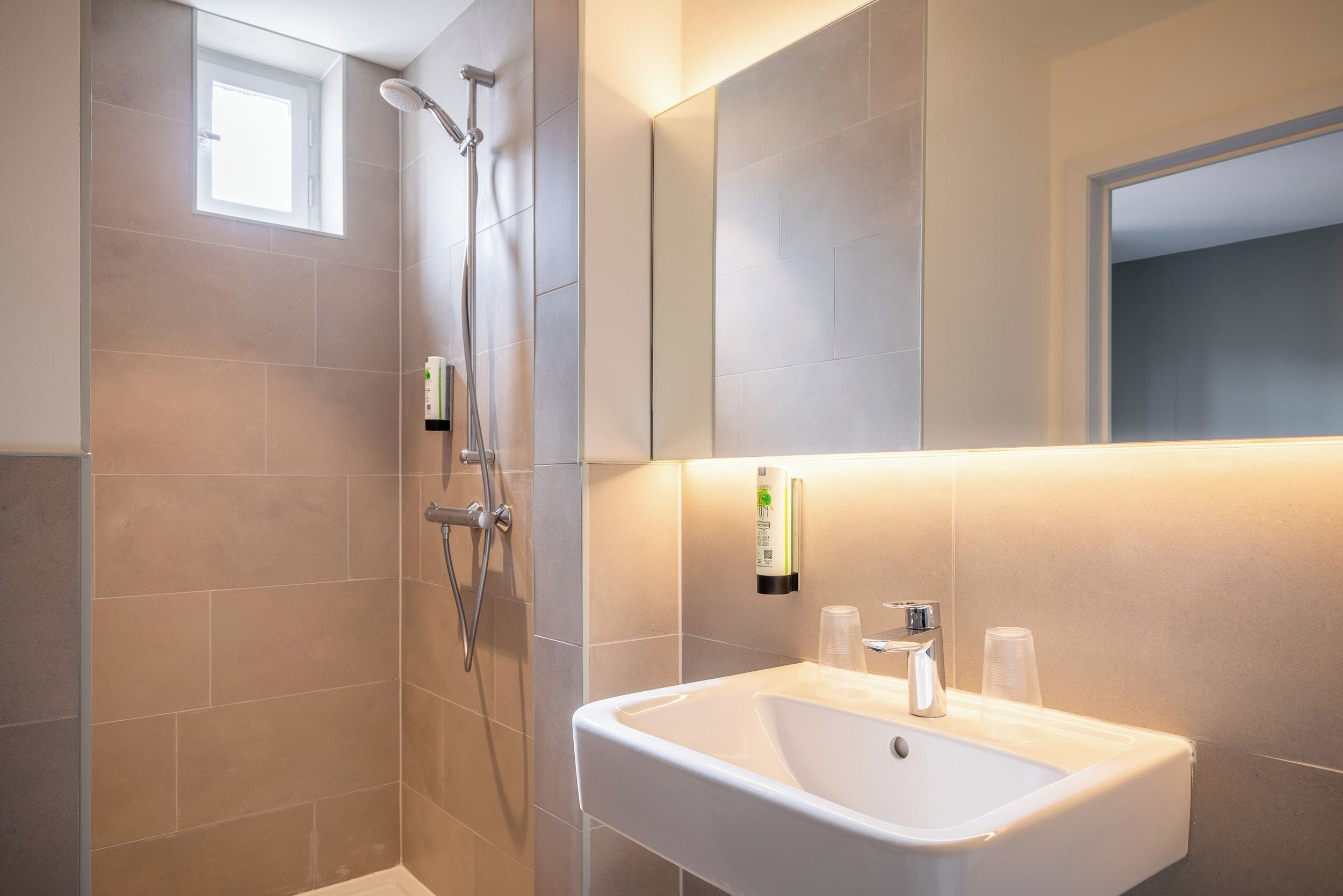 Une salle de bain moderne avec une douche, un lavabo et un miroir.