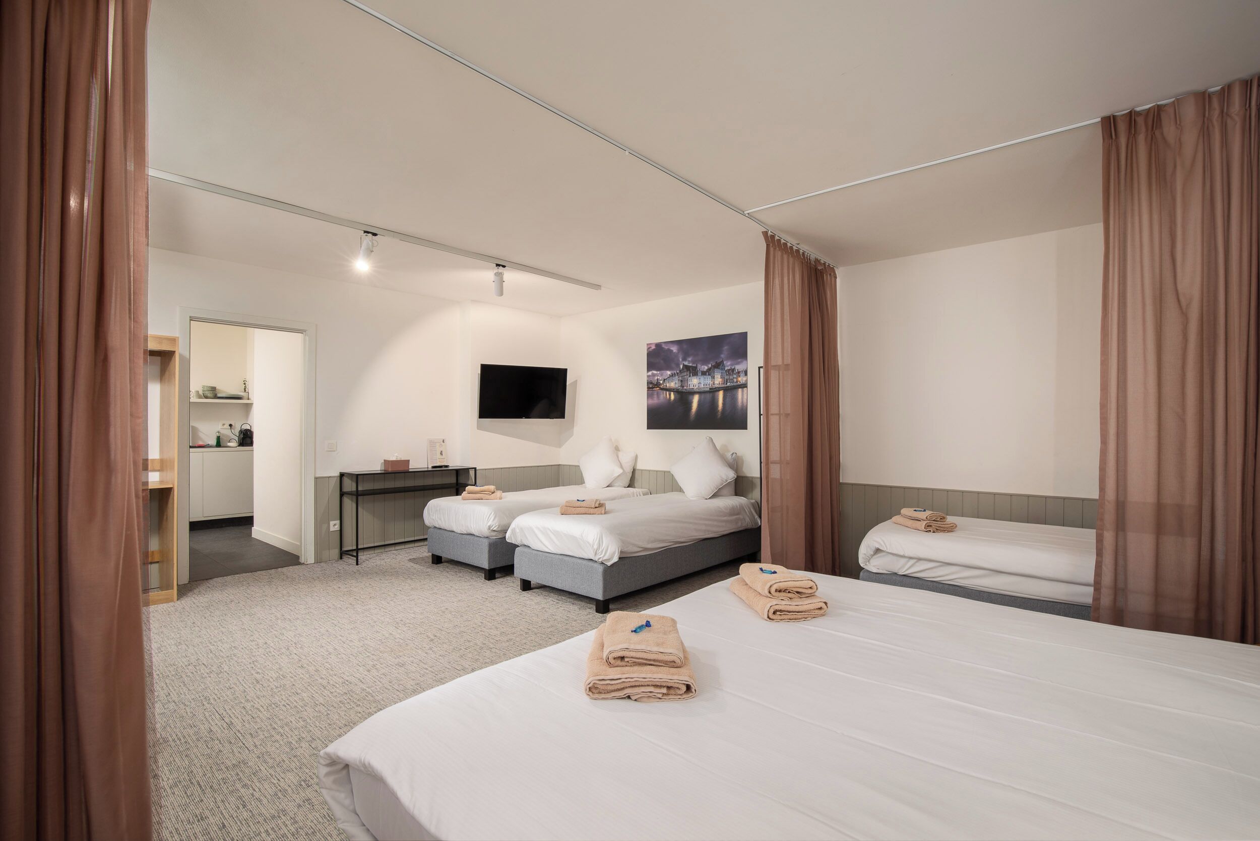 Ein Hotelzimmer mit zwei Betten, einem Fernseher, einem Gemälde und einem durchgegangenen Tür erkennbaren Badezimmer.