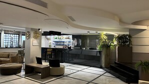 A modern lobby with a bar area, seating arrangements, and a staircase leading to an upper floor. - Floris Arlequin Grand Place (Brussels)