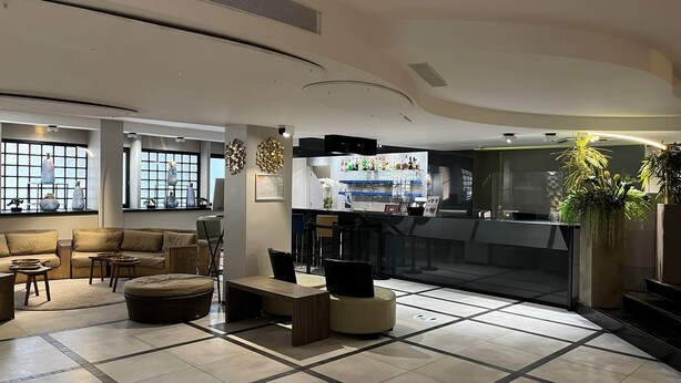 A modern hotel lobby with a seating area, a bar, and a large window. - Floris Arlequin Grand Place (Brussels)