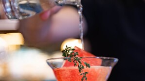 Un cóctel con guarnición siendo vertido en una copa de martini.