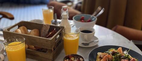 A breakfast setting with a variety of dishes, including a bowl of cereal, a plate of salad, and a pot of soup garnished with cilantro. There are also glasses of orange juice and a bottle of milk on the table.