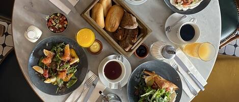 A round dining table with various dishes, including a salad, bread, and a bowl of fruit.