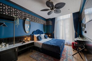 Un dormitorio moderno con una cama grande, un ventilador de techo, un espejo y una mesita de noche con lámpara.
