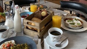 Un restaurante con bufé de desayuno, que ofrece diferentes platos, bebidas y una zona de bar con estantes llenos de botellas.