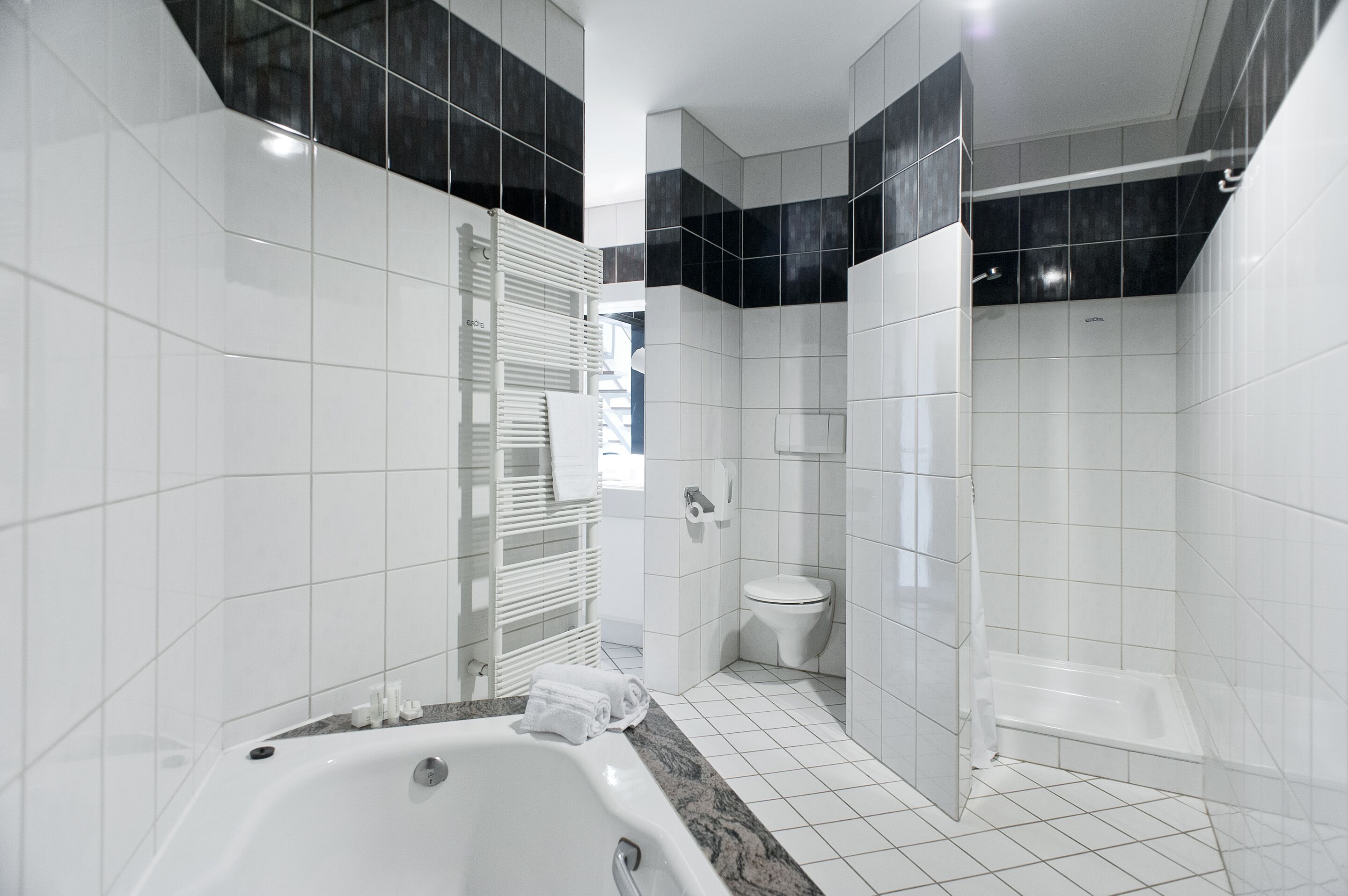 Ein modernes Badezimmer mit Badewanne, Toilette und Dusche.