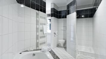 Ein modernes Badezimmer mit Badewanne, Toilette und Dusche.