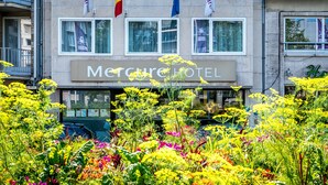 Hotelli nimeltä Mercure Hotel, jossa on useita lippuja, mukaan lukien Euroopan unionin lippu, sekä kukka-aiheinen kyltti.