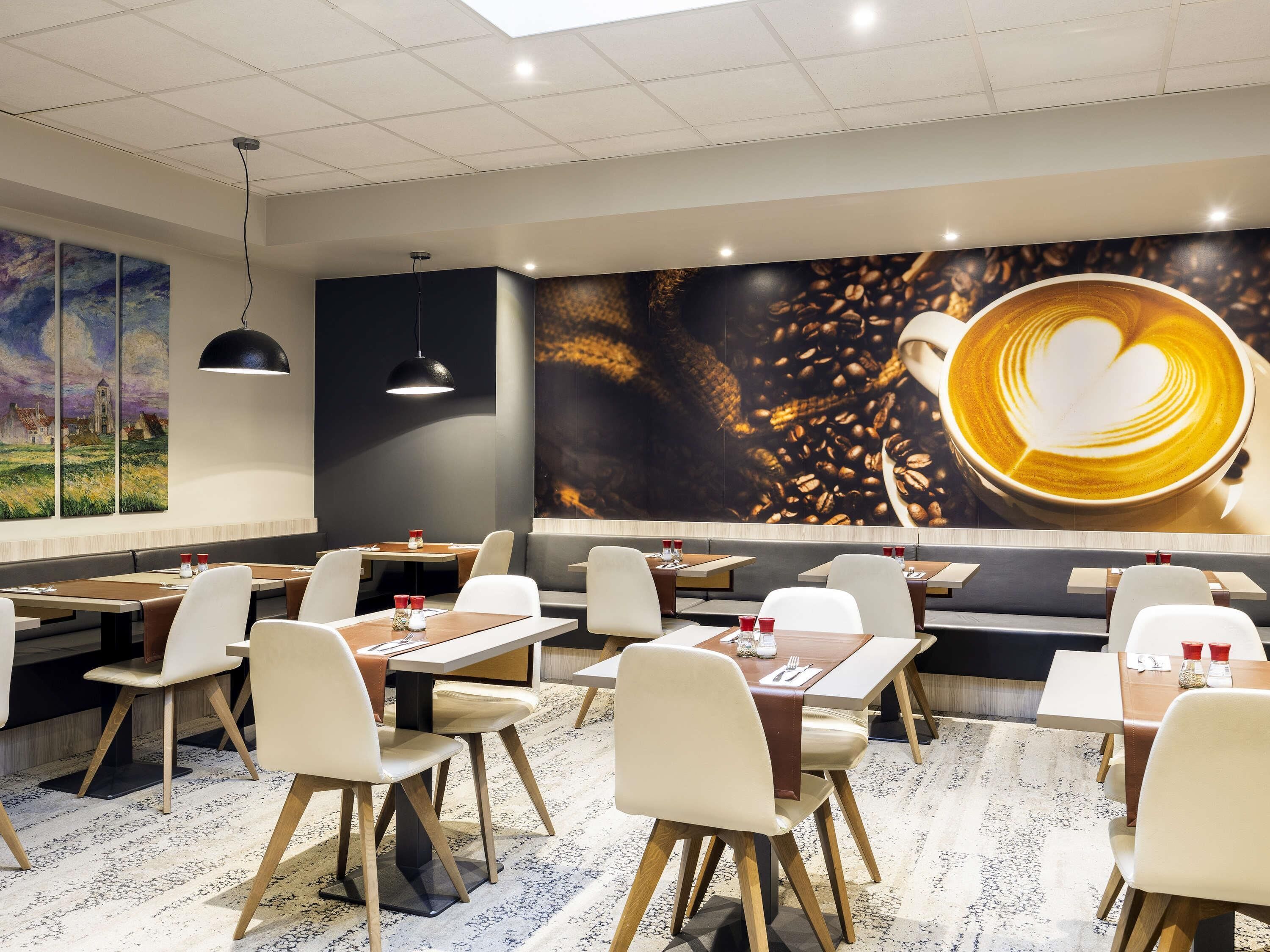 A modern restaurant interior with tables, chairs, and a large coffee-themed mural.