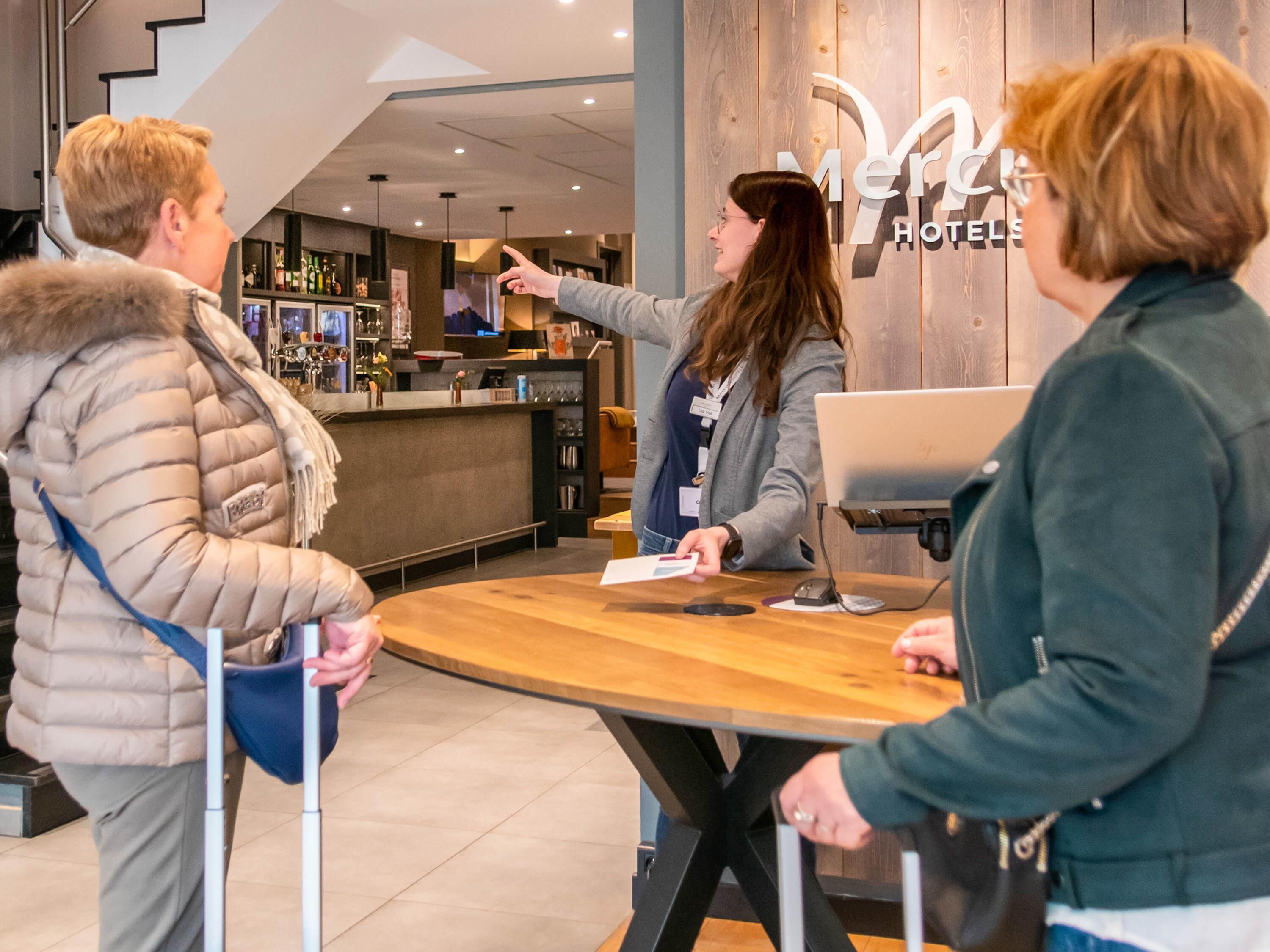A hotel reception area with a wooden counter, a computer, and a sign that reads "Merry Hotels".