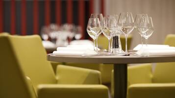 A dining table with multiple wine glasses and plates, set against a backdrop of yellow chairs and a striped wall.