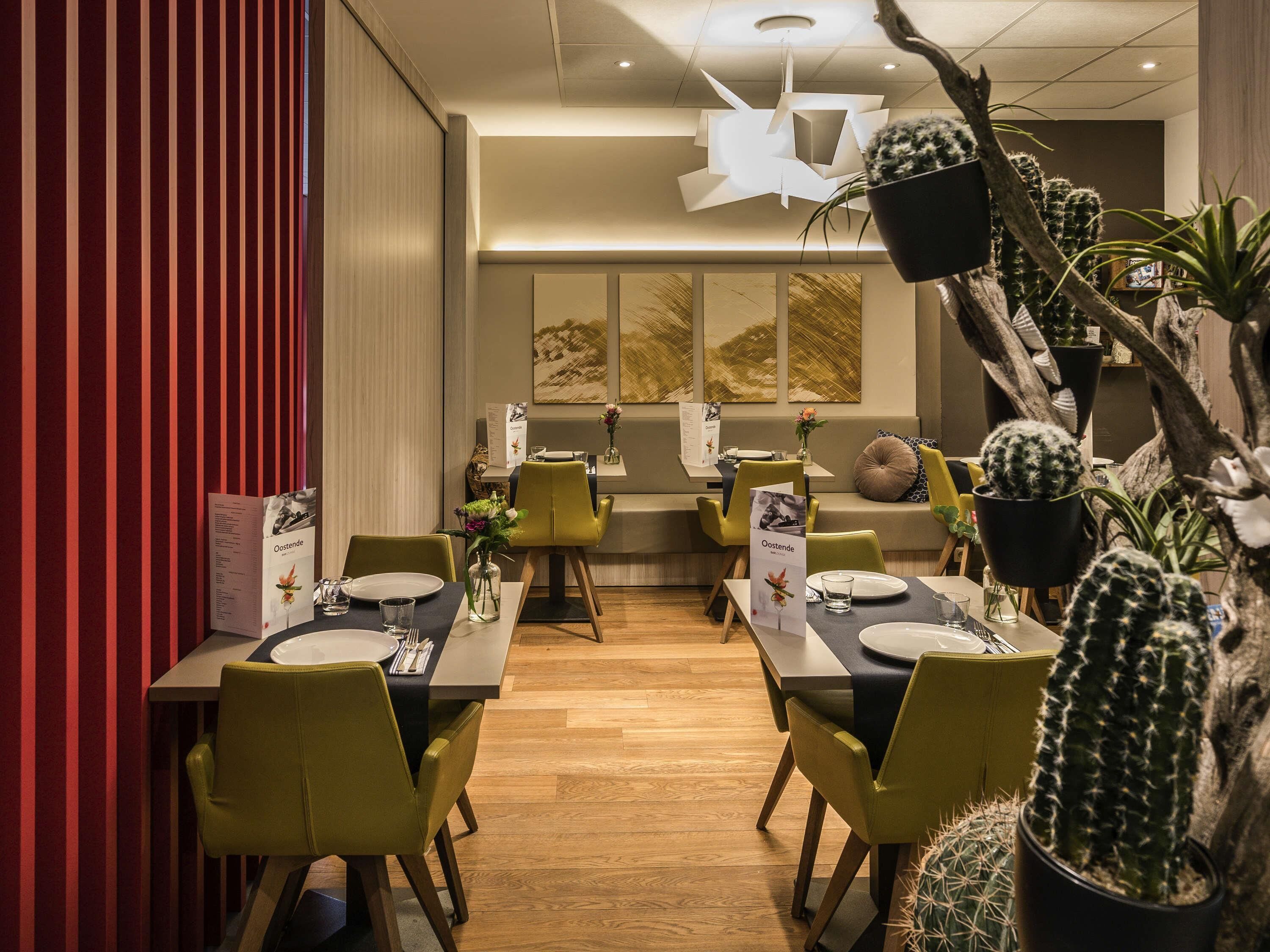A restaurant with wooden flooring, green chairs, and cactus decorations.