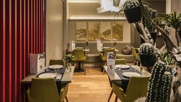 Un restaurant avec un plancher en bois, des chaises vertes et des décorations à thème de cactus.