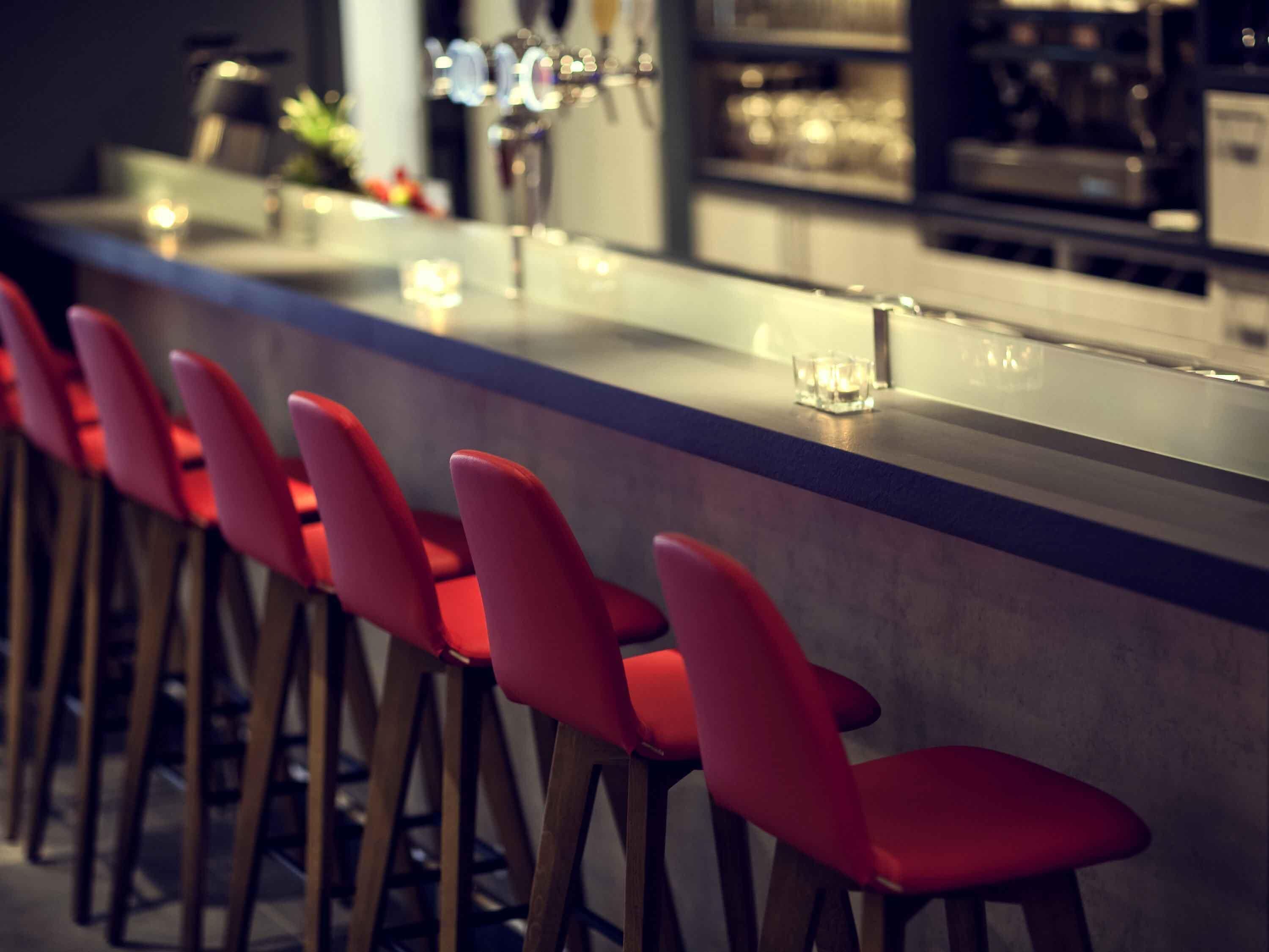 Un'area bar con sedie rosse e un bancone.
