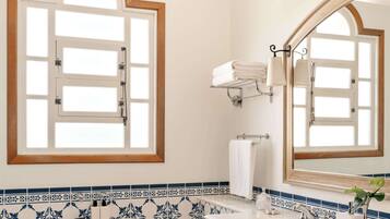 A bathroom with a bathtub, two sinks, a large mirror, and a window with a wooden frame.