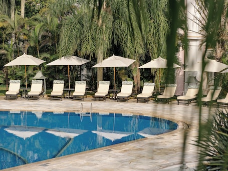 Una piscina al aire libre, sombrillas, sillones reclinables de piscina