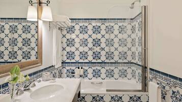 Une salle de bain avec un lavabo blanc, un miroir et une douche dont les carreaux sont ornés de motifs bleus et blancs.