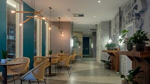 Un café moderne avec des chaises en osier, des tables en bois et des plantes en pot.