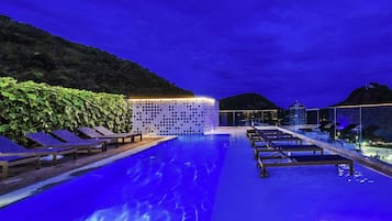 Una piscina al aire libre, sillones reclinables de piscina