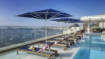 Una piscina al aire libre, sillones reclinables de piscina