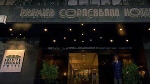 Exterior del Hotel Premier Copacabana, con un cartel sobre la entrada y una persona uniformada de pie al frente.