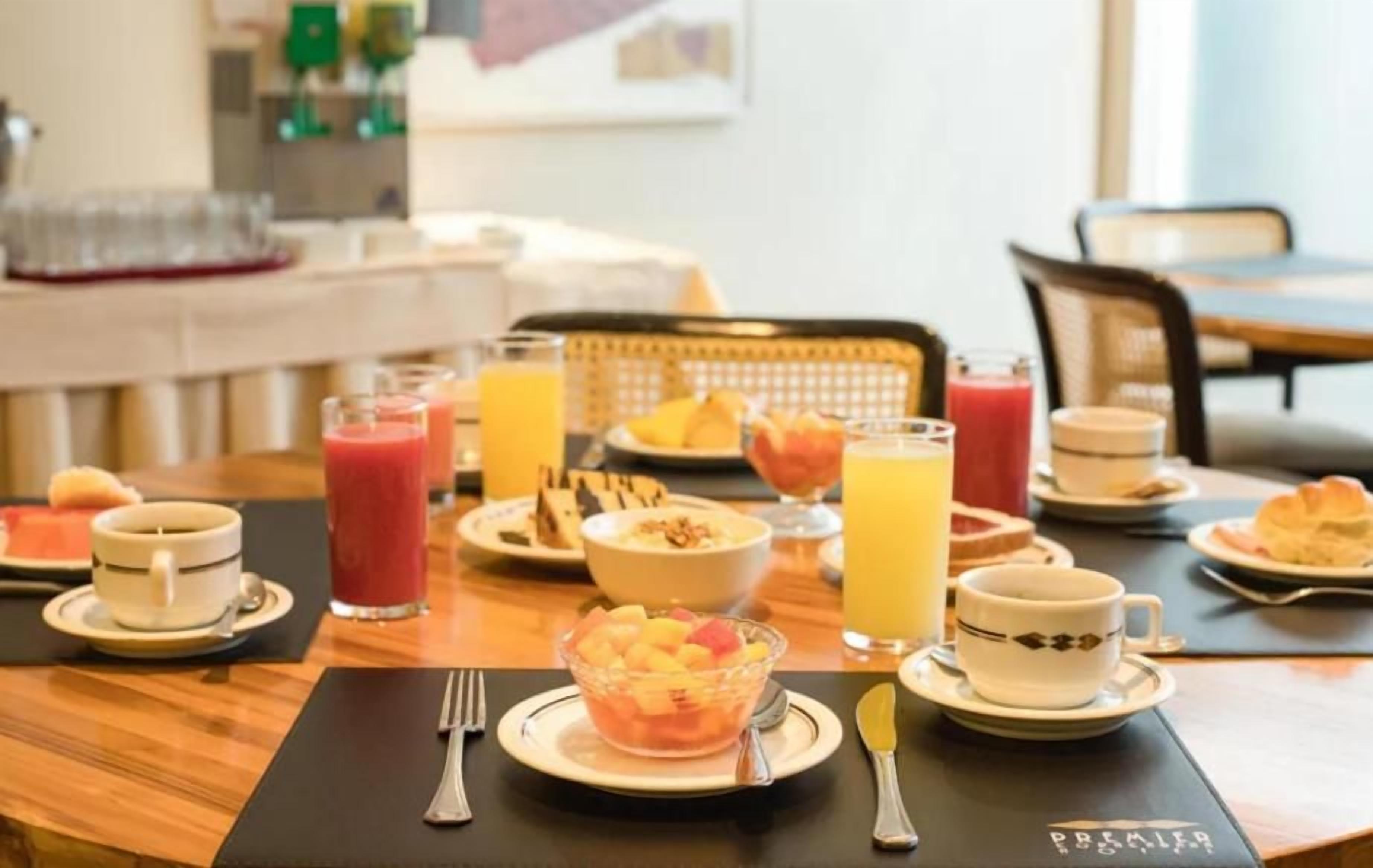Une table dressée pour le petit-déjeuner, avec différents plats, boissons et couverts.