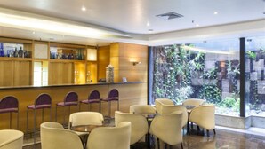 Un hall de hotel con una recepción, zona de estar y vistas a un jardín a través de amplias ventanas.