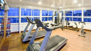 Un gimnasio con cintas de correr, máquinas de pesas y una máquina de remo.
