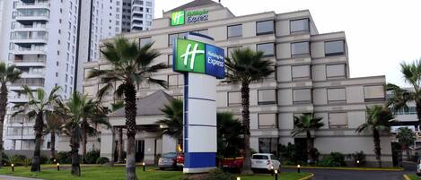 A Holiday Inn Express hotel with a prominent sign, surrounded by palm trees and a parking lot.